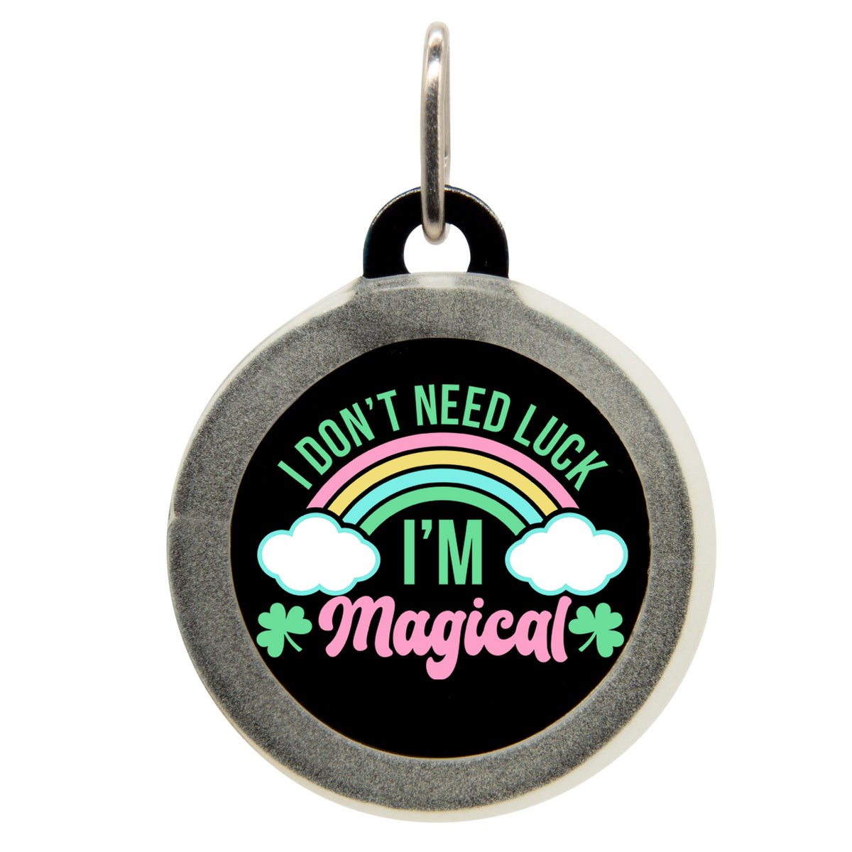 A black pet ID tag with the text &quot;I DON&#39;T NEED LUCK, I&#39;M Magical&quot; in colorful fonts, featuring a rainbow, clouds, and a shamrock. The tag has a small metal loop at the top for attaching to a collar.