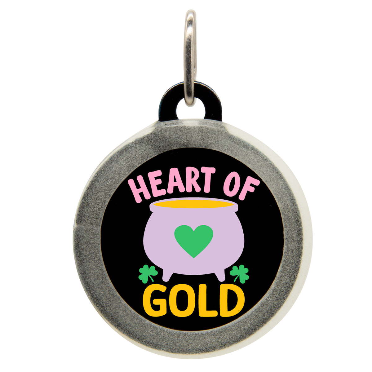 A black pet ID tag with the text &quot;HEART OF GOLD&quot; in pink and yellow, featuring a purple pot with a green heart and shamrocks. The tag has a small metal loop at the top for attaching to a collar.