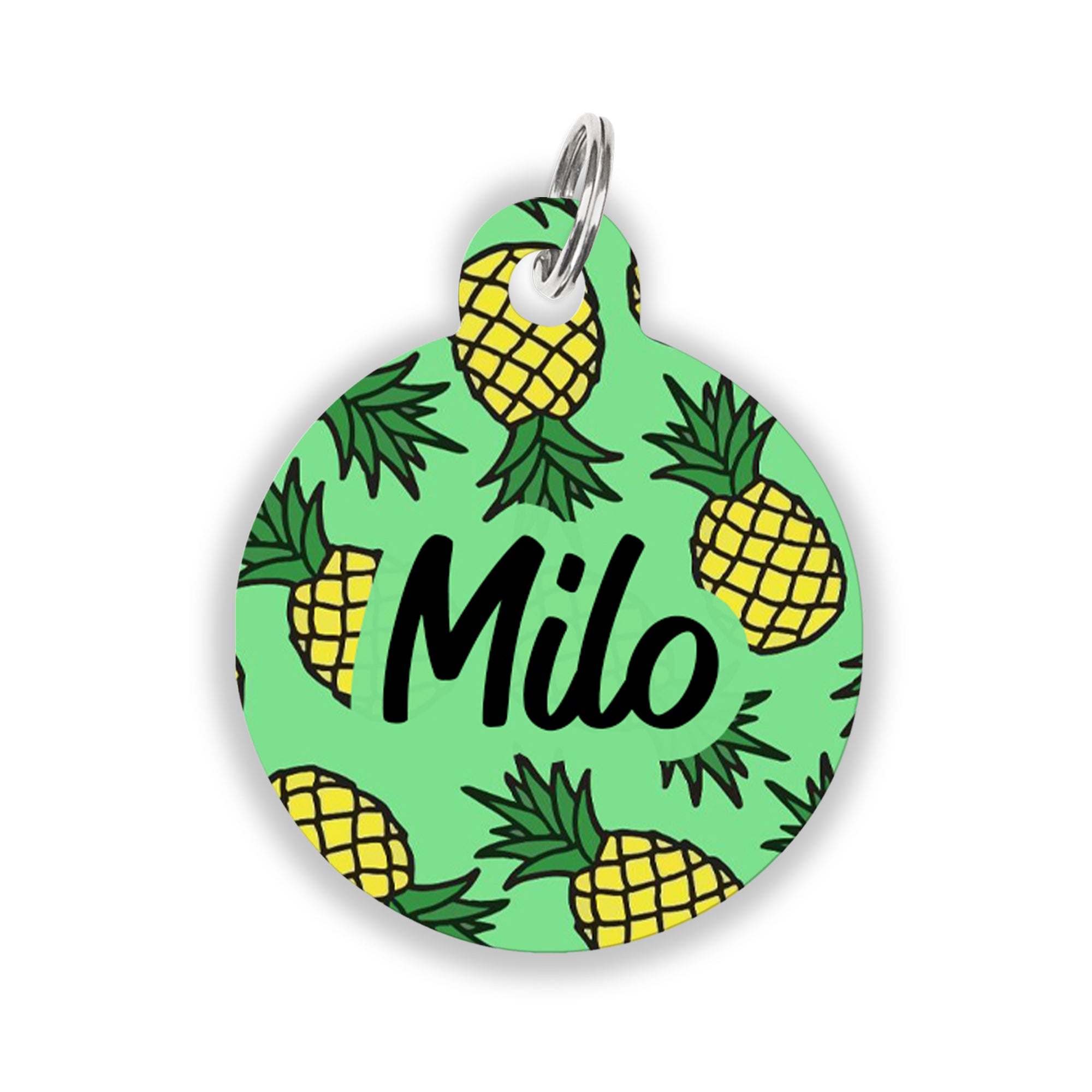 A round green pet ID tag decorated with bright yellow pineapples and the name "Milo" in bold black script, attached to a silver keyring.