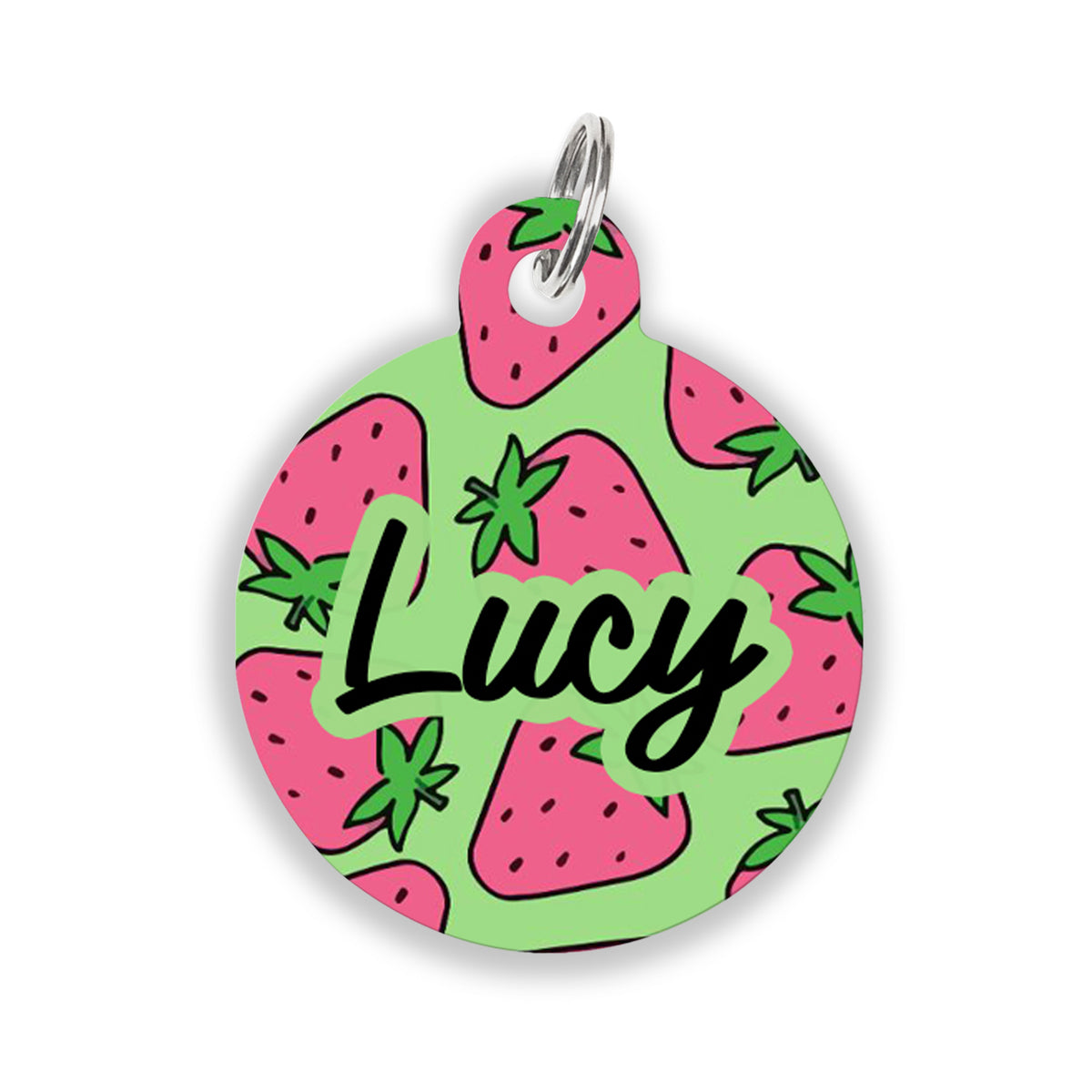 A round pet ID tag with a green background covered in pink strawberries and the name “Lucy” written in bold black script, attached to a silver keyring.